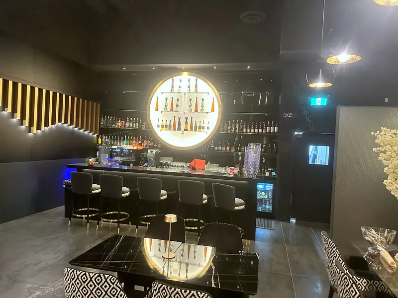 Bar counter with an illuminated bottle display, pendant lighting and seating