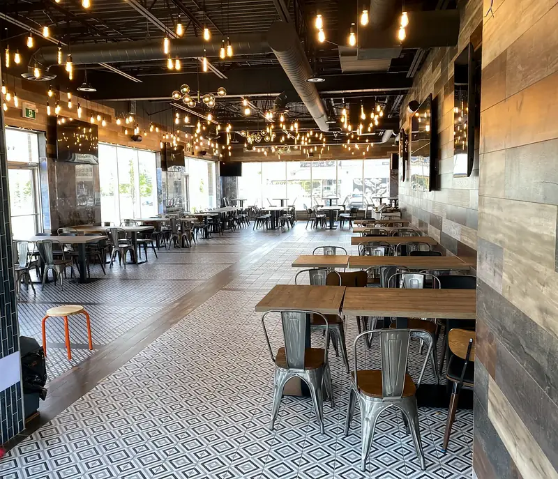 Restaurant dining room with timber tables, patterned flooring and pendant lights